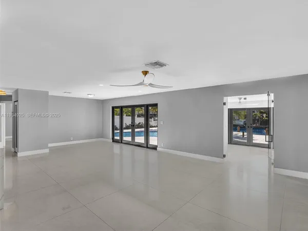 an empty room with windows and ceiling fan