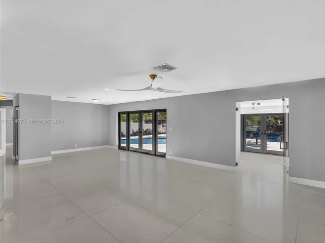 an empty room with windows and ceiling fan