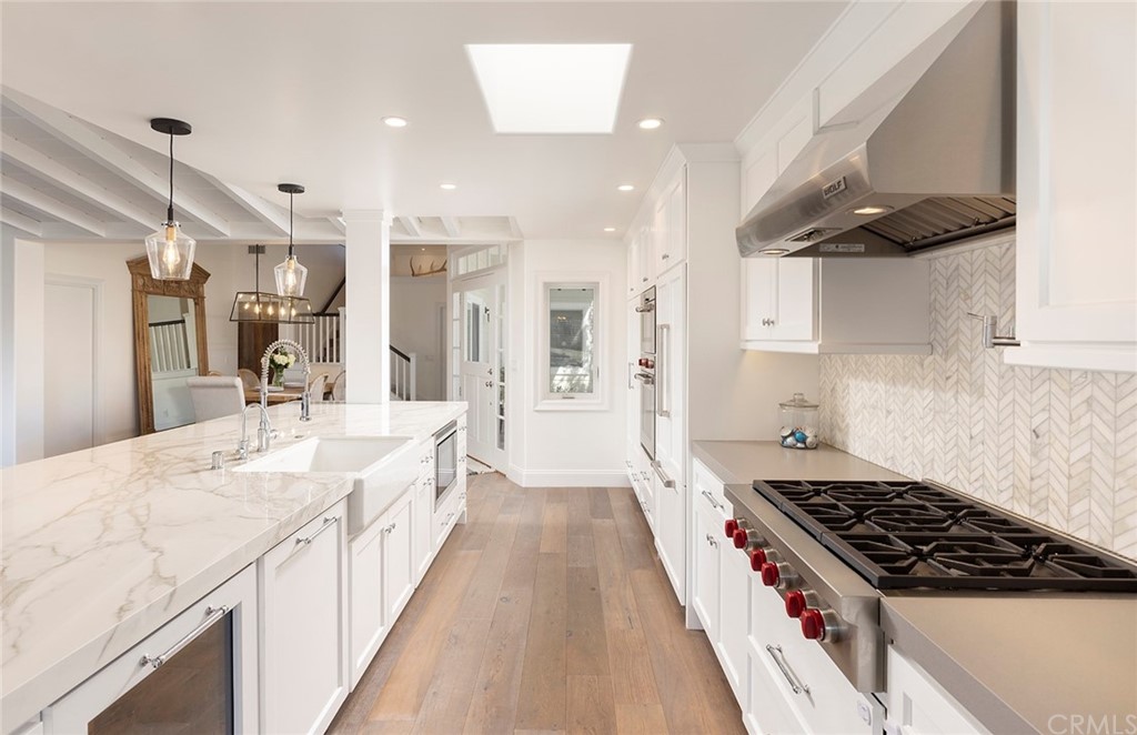 56 Balboa Newport Beach, CA 92663 - Photo 10 of 37 a large kitchen with kitchen island a stove a sink dishwasher and a dining table with wooden floor
