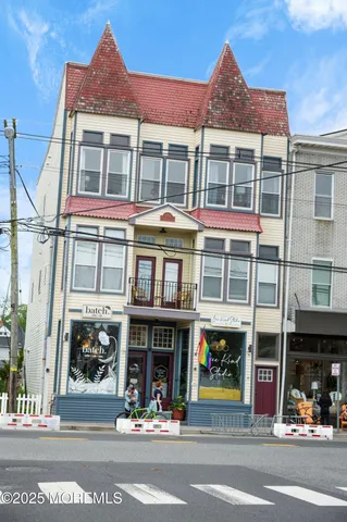 a view of a white house with large windows and a small yard