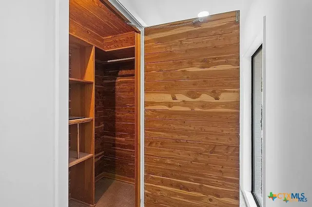 a view of an empty room with wooden floor and a ceiling fan