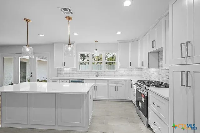 a kitchen with a stove a sink a refrigerator and white cabinets