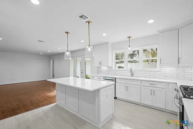 a large kitchen with kitchen island a sink a stove a refrigerator and white cabinets