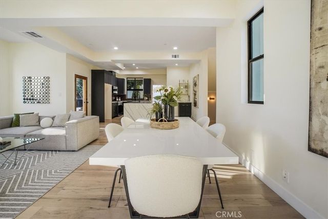 a kitchen with stainless steel appliances kitchen island granite countertop a refrigerator a stove top oven a sink dishwasher and white cabinets with wooden floor