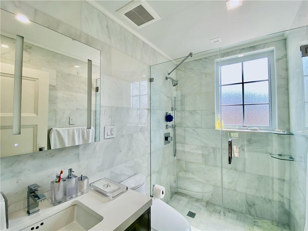 222 Exeter Street Brooklyn, NY 11235 - Photo 22 of 39 a bathroom with a shower sink and mirror