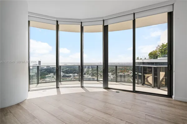 a view of an empty room with wooden floor and iron stairs