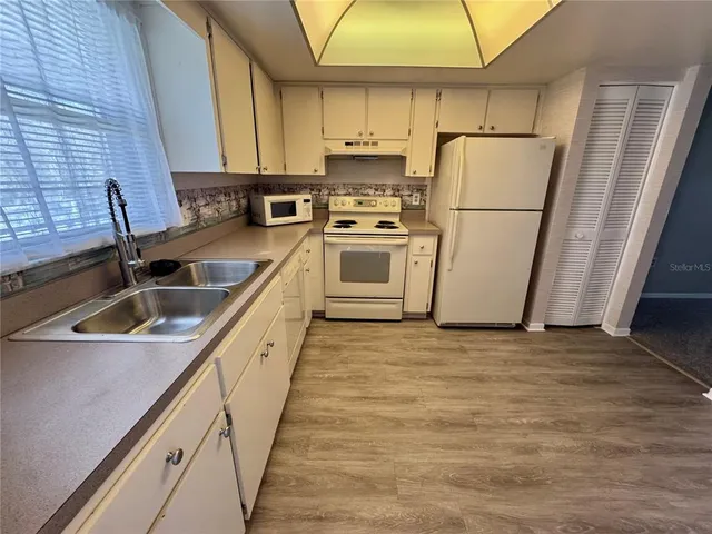 a kitchen with white cabinets and white appliances