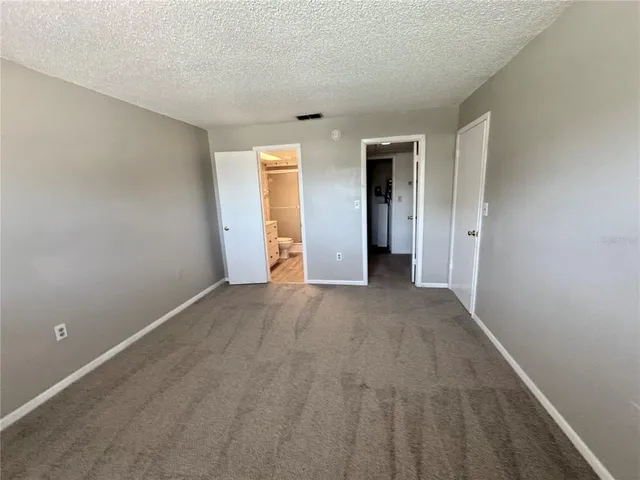 a view of an empty room with closet and a window