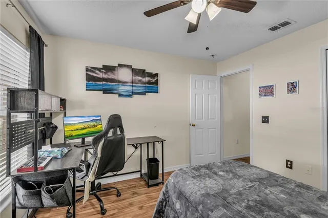 a bedroom with a bed a desk and chair with wooden floor