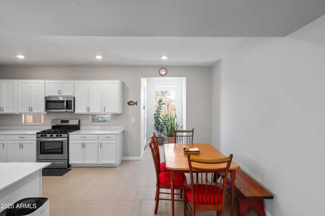 a kitchen with stainless steel appliances kitchen island granite countertop a sink a stove a table and chairs