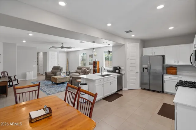 a living room with stainless steel appliances furniture a couch and a kitchen view