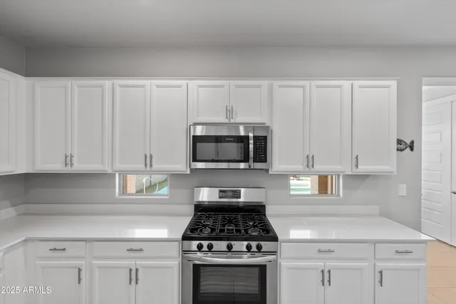 a kitchen with white cabinets and appliances