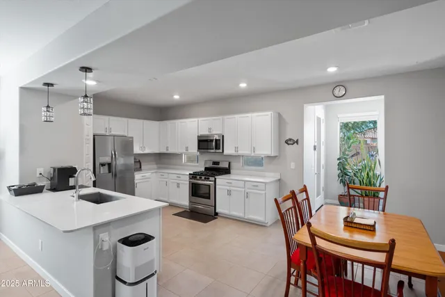 a kitchen with a dining table chairs stainless steel appliances and cabinets