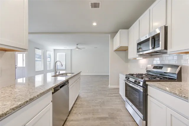 a kitchen with stainless steel appliances granite countertop a stove a sink and a microwave