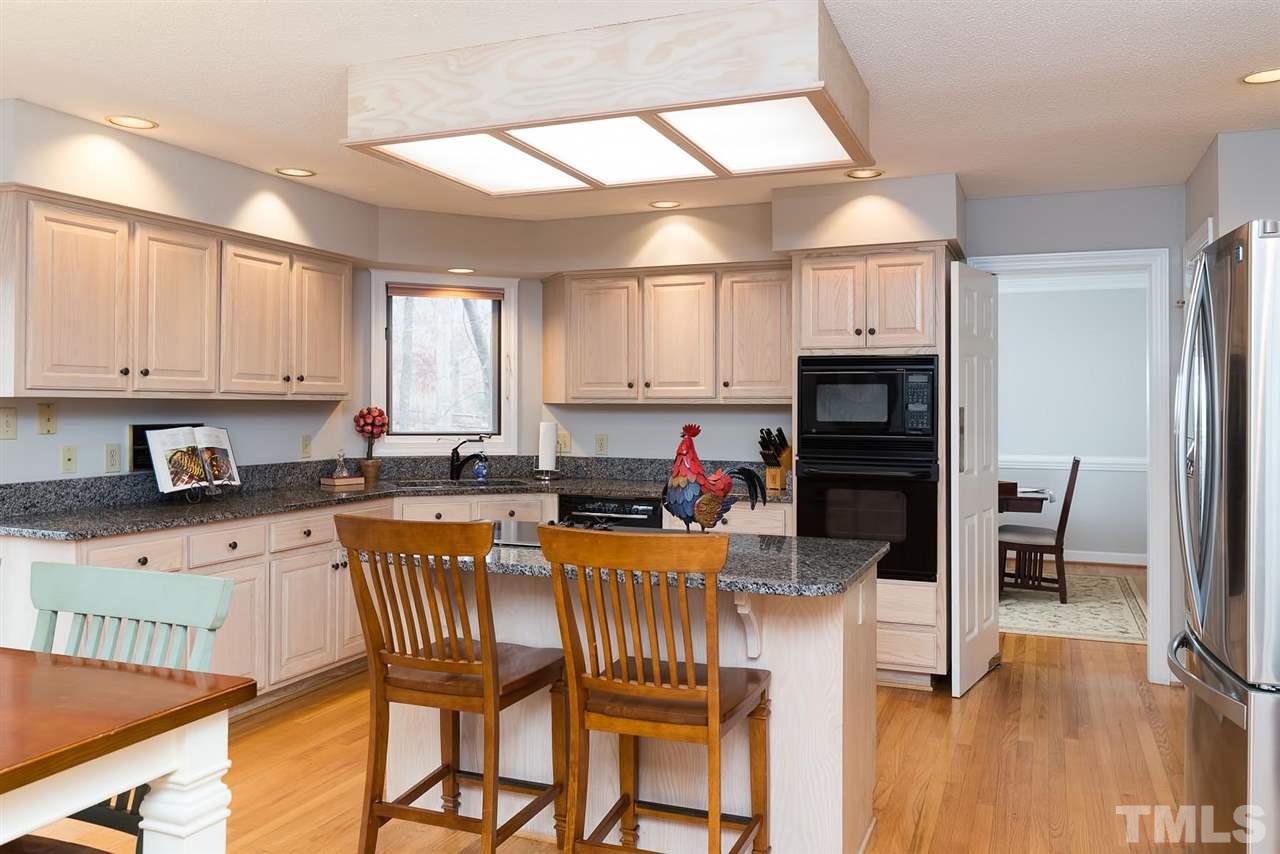 8816 Ross Court Raleigh, NC 27613 - Photo 7 of 25 a kitchen with stainless steel appliances kitchen island granite countertop a refrigerator a stove a dining table and chairs with wooden floor