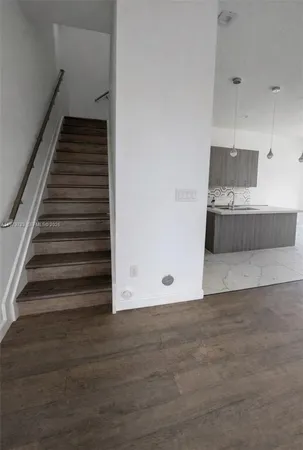 a view of an empty room with wooden floor and stairs