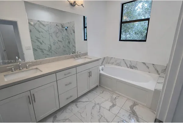 a spacious bathroom with a tub sink and mirror