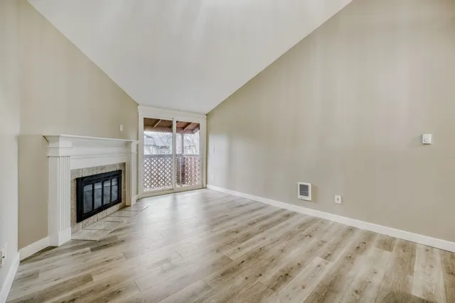 a view of an empty room with a fireplace and a window
