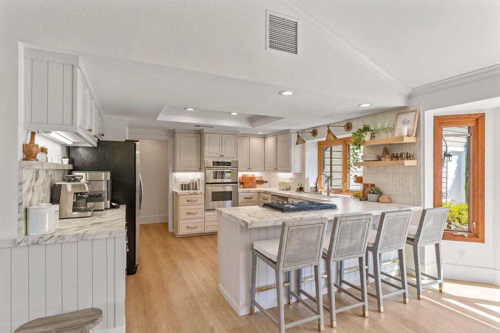3355 Lone Jack Road Encinitas, CA 92024 - Photo 27 of 54 a kitchen with stainless steel appliances kitchen island granite countertop a table chairs and a refrigerator