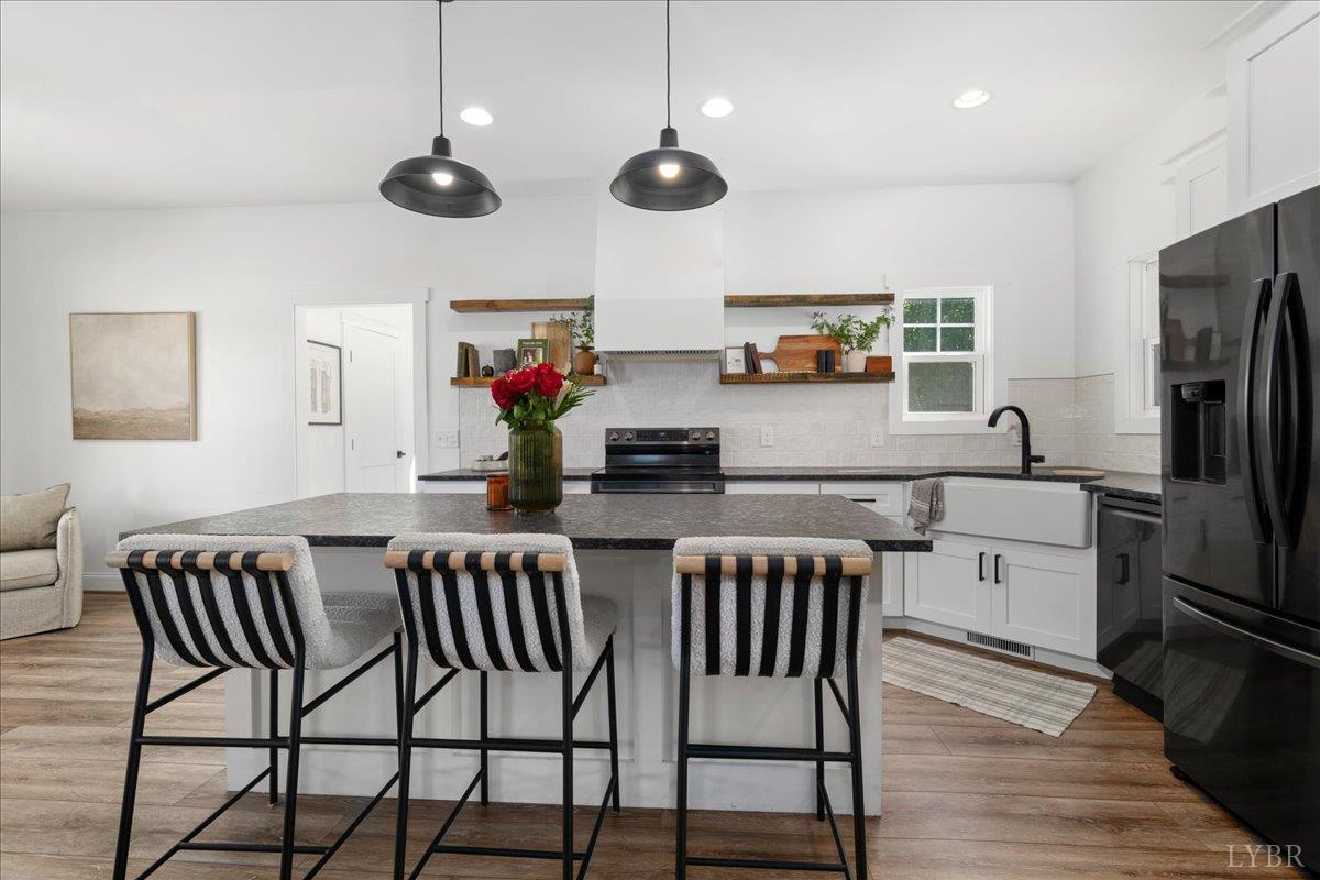 1393 Stonewall Road Concord, VA 24538 - Photo 15 of 85 a kitchen with stainless steel appliances granite countertop a stove a refrigerator a kitchen island a dining table and chairs with wooden floor