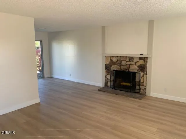 a view of an empty room with wooden floor fireplace and a window
