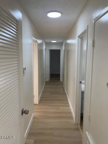 a view of a hallway with wooden floor and closet