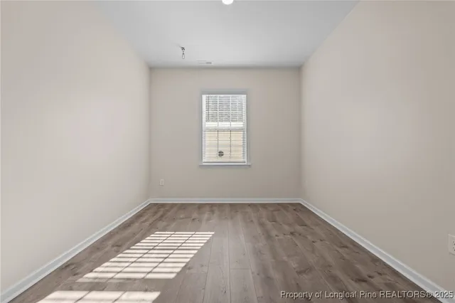 a view of empty room with wooden floor and fireplace