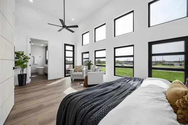 a large bedroom with a bed a chandelier and large windows