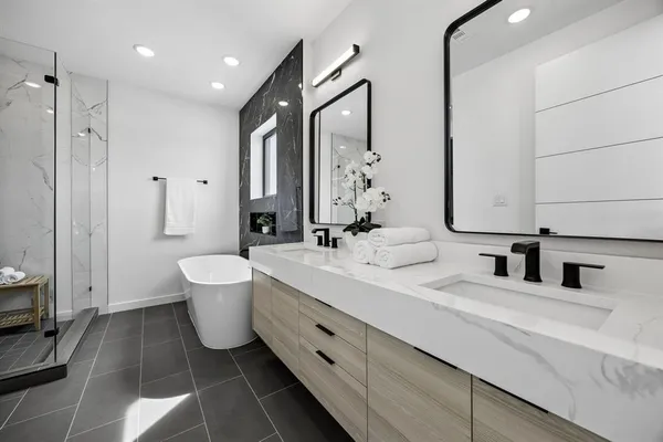 a bathroom with double vanity sinks a toilet a mirror and shower