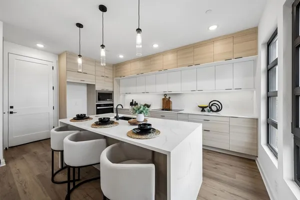 a kitchen with a sink stove and white cabinets with wooden floor