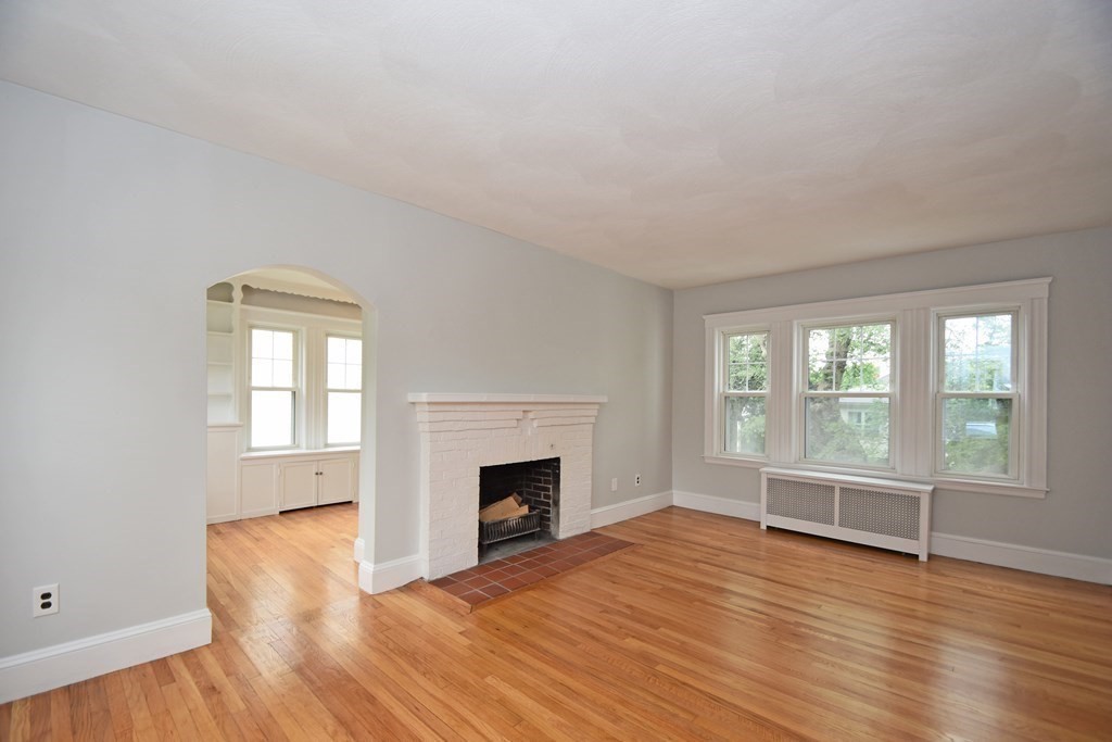 87 Standish Road Watertown, MA 02472 - Photo 5 of 27 an empty room with wooden floor fireplace and windows