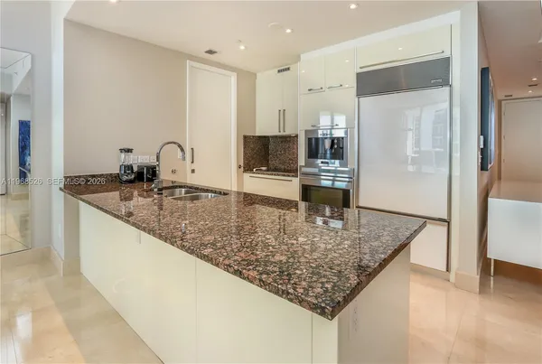 a kitchen with stainless steel appliances granite countertop a sink and a refrigerator
