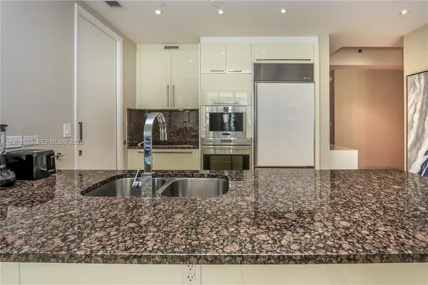 a large kitchen with kitchen island a large counter top stainless steel appliances and cabinets