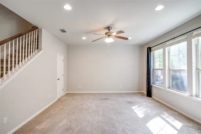 en empty room with windows and ceiling fan