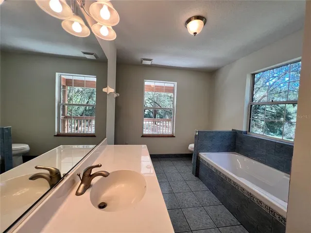 a bathroom with a tub a sink and a large mirror