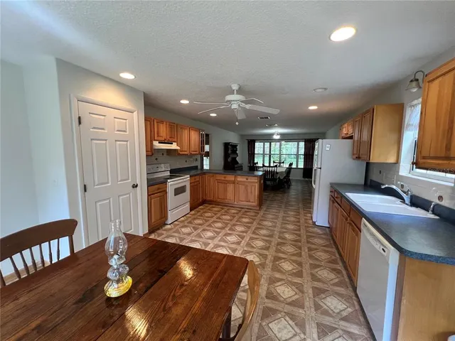 a large kitchen with stainless steel appliances granite countertop a refrigerator a sink dishwasher a dining table and chairs with wooden floor