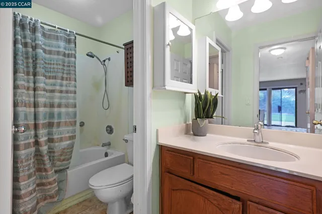 a bathroom with a granite countertop sink a toilet a mirror a vanity and shower