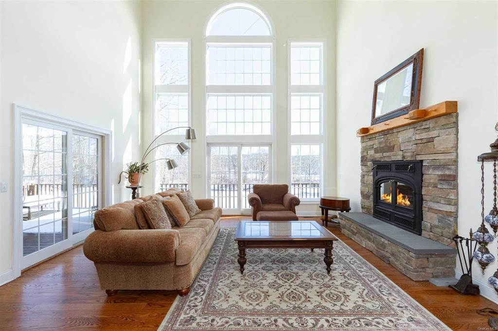 a living room with furniture a rug a large window and a fireplace