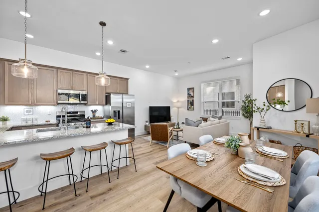 a kitchen with a dining table chairs stove and white cabinets with wooden floor