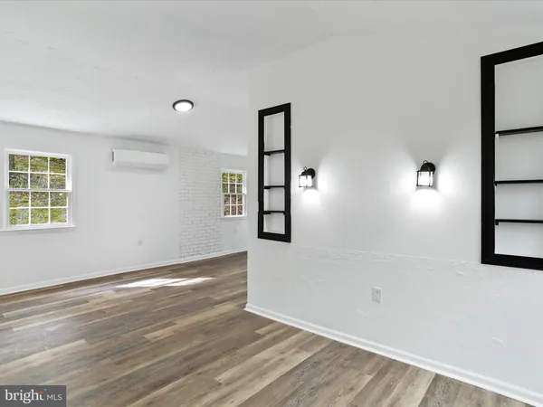 a view of an empty room with window and wooden floor