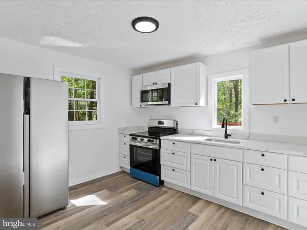 a kitchen with white cabinets and window