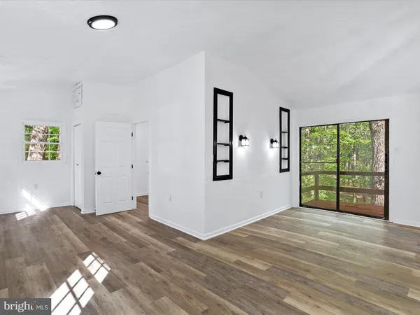 a view of an empty room with window and wooden floor