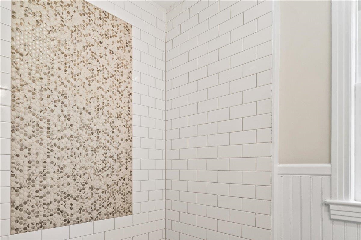 170 South Greer Street Memphis, TN 38111 - Photo 30 of 35 Shower enclosure featuring white subway tile walls and a decorative pebble-style tile accent panel