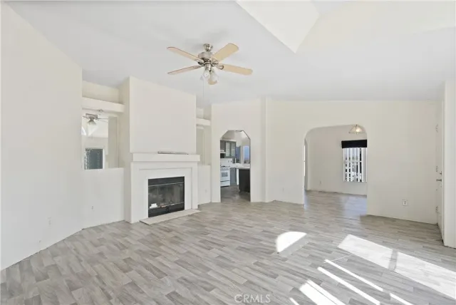 a view of a livingroom with a fireplace a ceiling fan and wooden floor