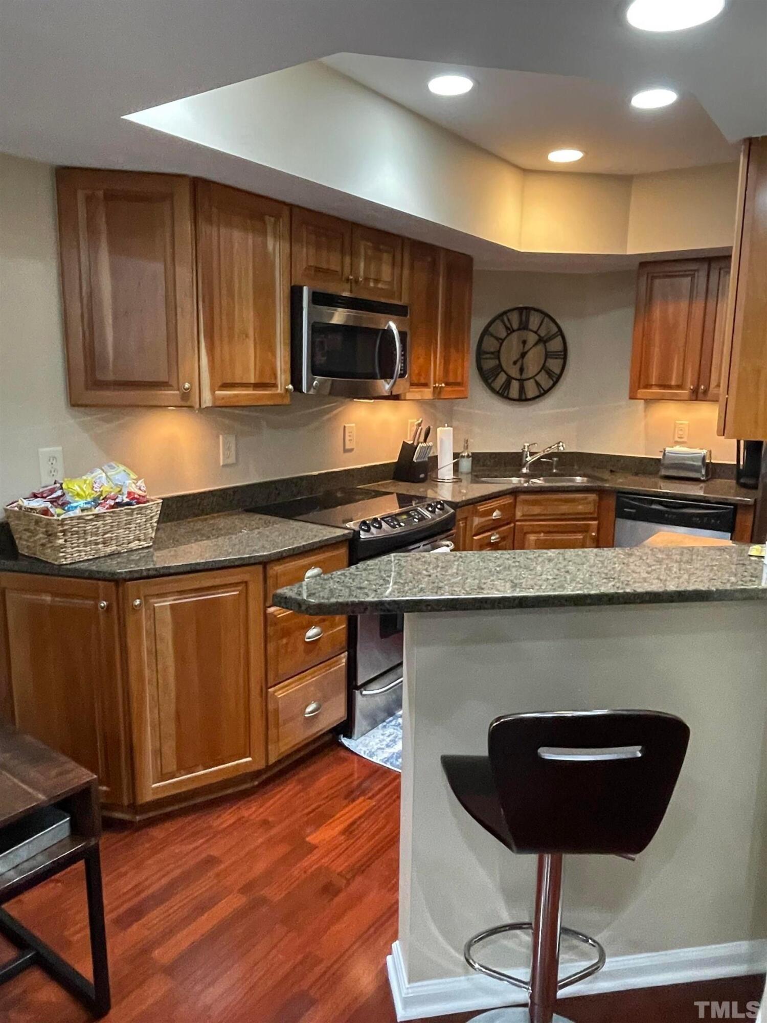720 Bilyeu Street, Unit 203 Raleigh, NC 27606 - Photo 5 of 13 a kitchen with stainless steel appliances granite countertop a stove a sink and a microwave