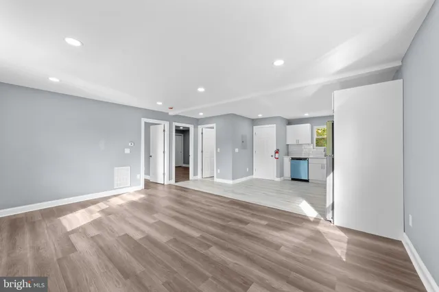a view of an empty room with wooden floor and windows