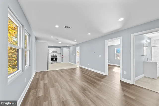 a view of an empty room with wooden floor and a window