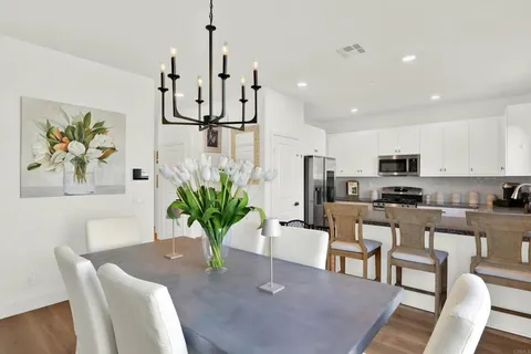 a dining room with furniture a potted plant and kitchen view