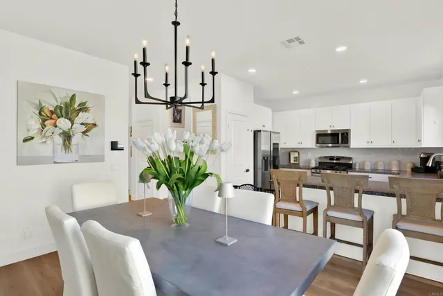 a dining room with furniture a potted plant and kitchen view