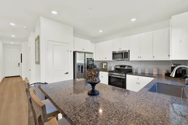 a kitchen with stainless steel appliances granite countertop a sink refrigerator and stove